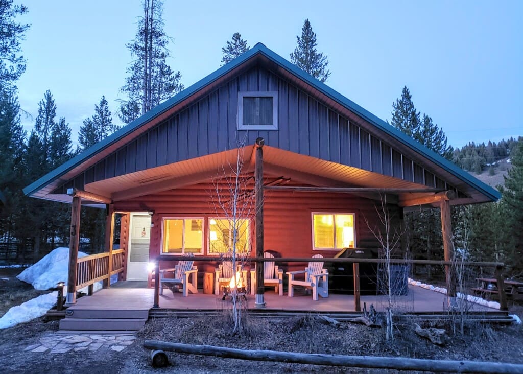Valley Creek Cabin glowing at twilight with lights on beneath the covered porch.