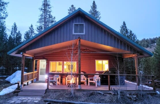 Valley Creek Cabin glowing at twilight with lights on beneath the covered porch.