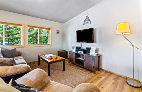 Living room TV area at Ponderosa Pine Cabin with seating and large windows.