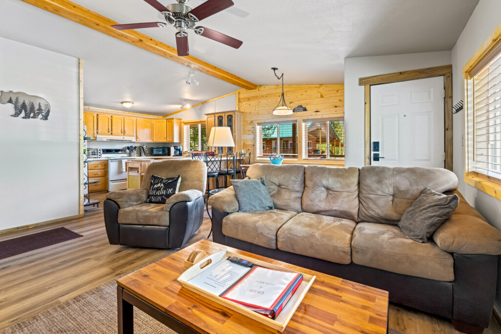 Ponderosa Pine Cabin living room with sofa, recliner and open kitchen behind it.