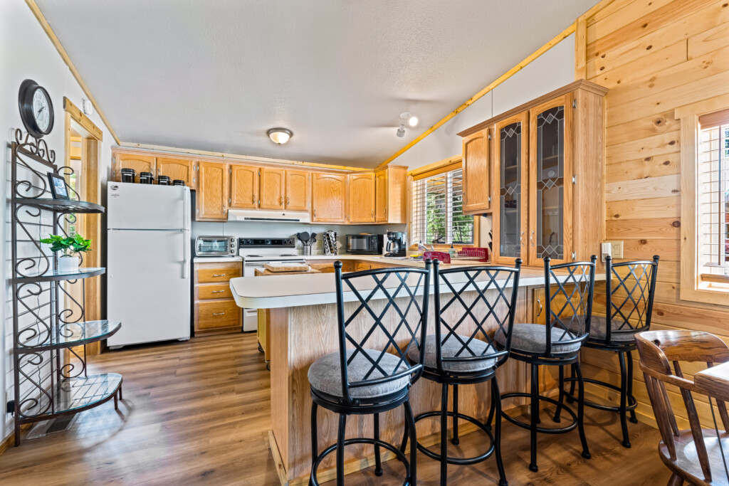 Ponderosa Pine Cabin kitchen with breakfast bar seating and wood cabinets.