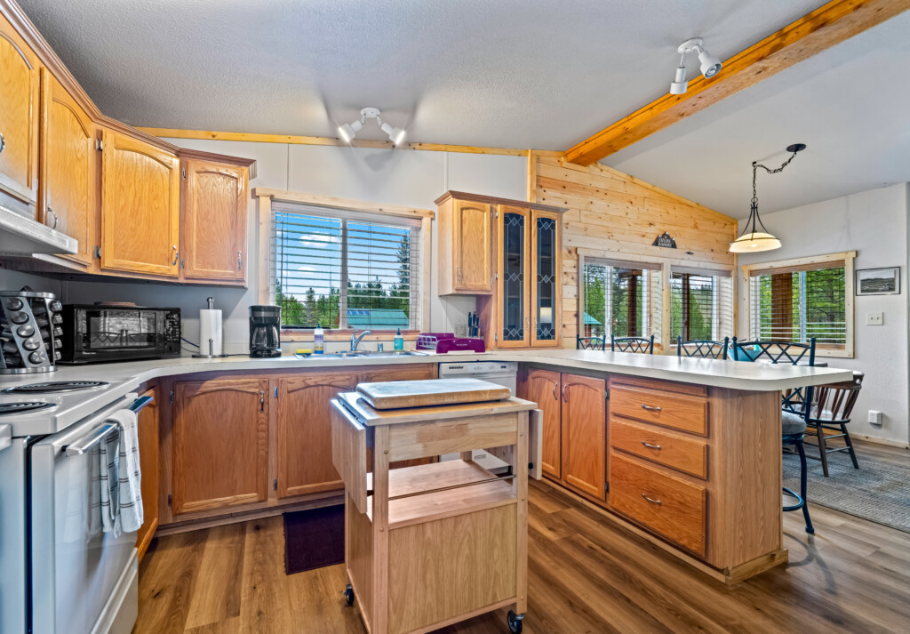 Full kitchen at Ponderosa Pine Cabin with wood cabinets, island and large windows.