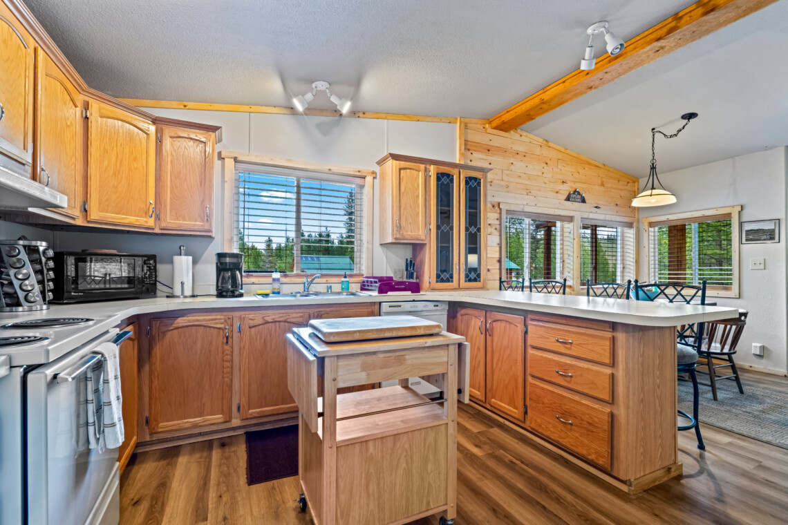 Full kitchen at Ponderosa Pine Cabin with wood cabinets, island and large windows.
