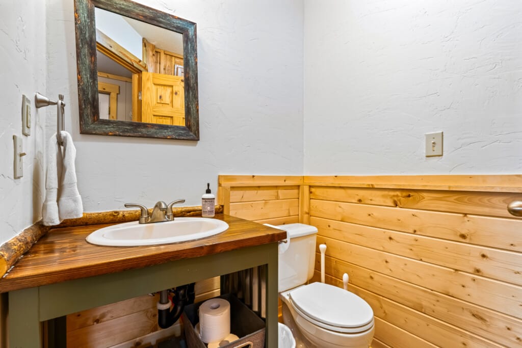 Second bathroom at Ponderosa Pine Cabin with sink, mirror and wood-paneled wall.