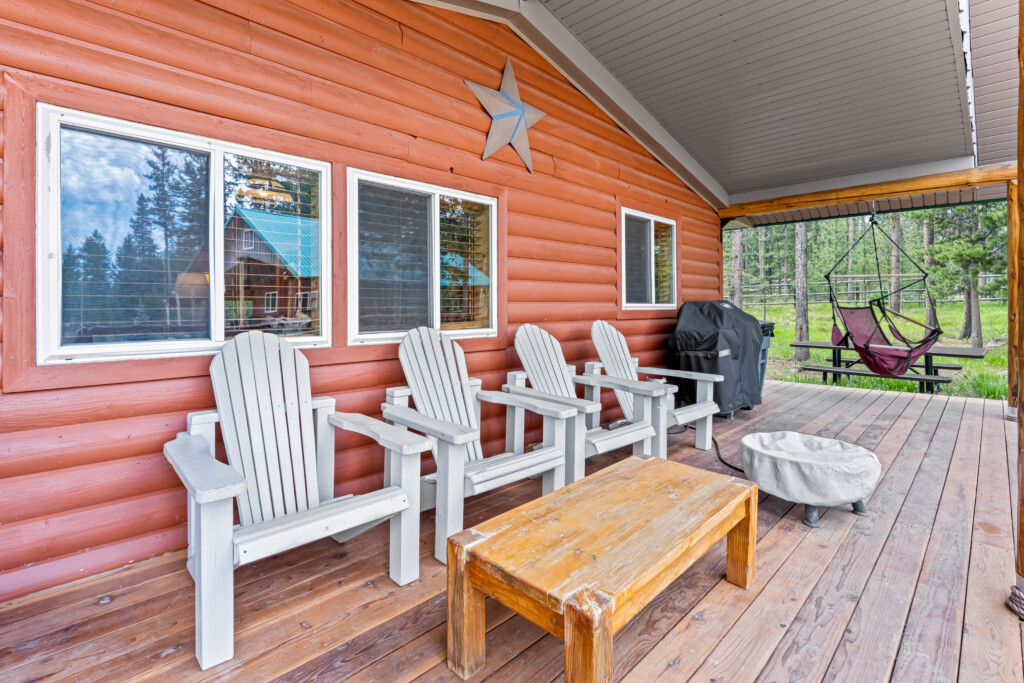 Covered porch at Ponderosa Pine Cabin with Adirondack chairs and outdoor seating.