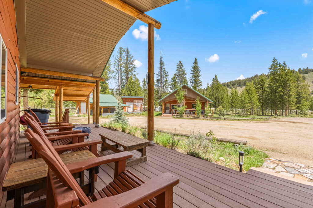 Covered porch at Bonanza Cabin with outdoor seating and views of the surrounding pine trees.