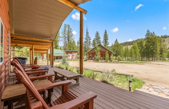 Covered porch at Bonanza Cabin with outdoor seating and views of the surrounding pine trees.