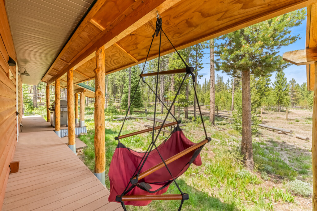 Chair swing on the covered porch overlooking the wooded grounds at Bonanza Cabin.