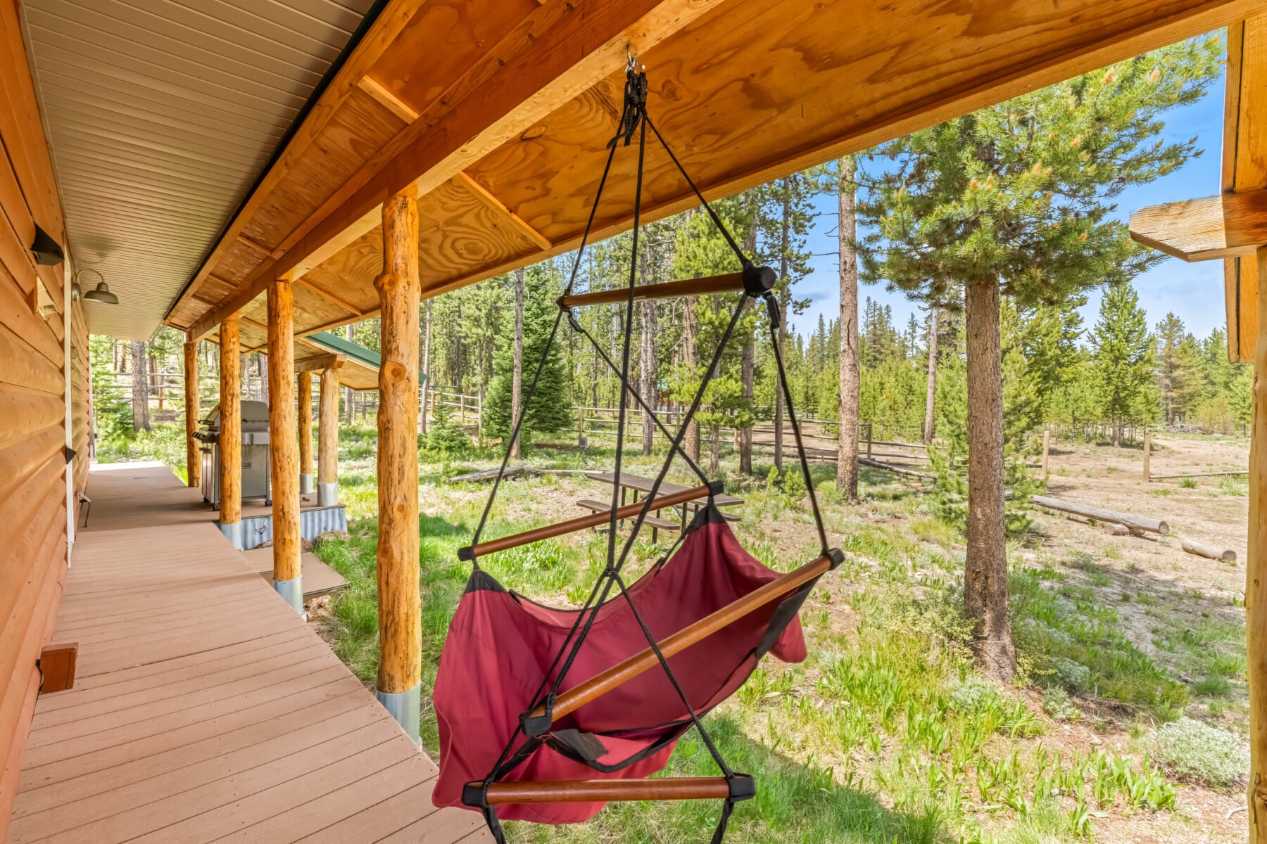 Chair swing on the covered porch overlooking the wooded grounds at Bonanza Cabin.