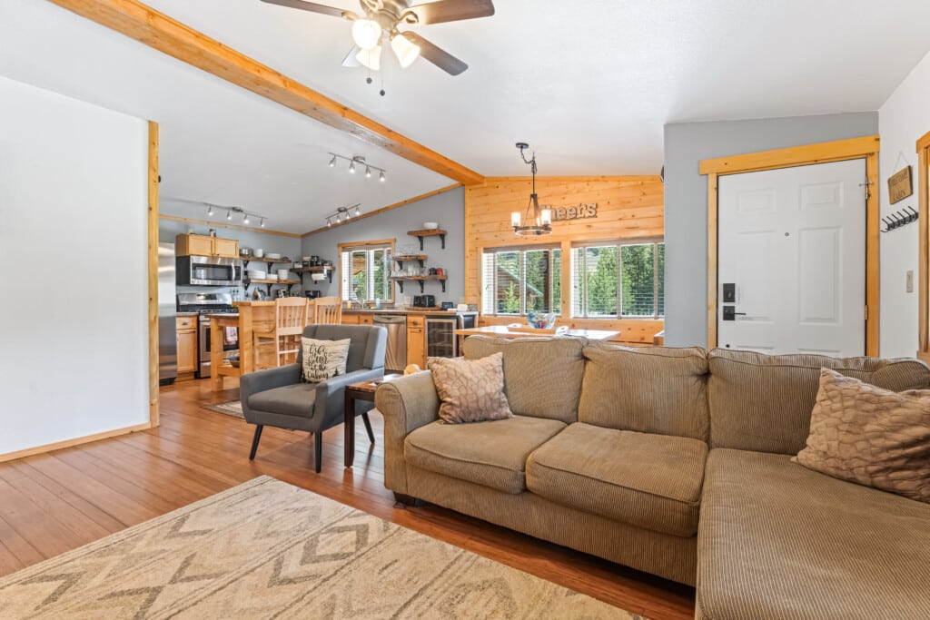 Open living and kitchen area at Bonanza Cabin with sectional sofa, dining space and full kitchen.