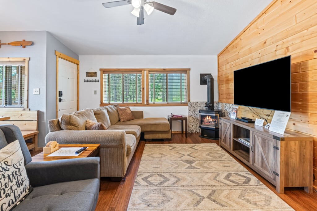 Bonanza Cabin living room with sectional sofa, TV, wood accent wall and gas stove.