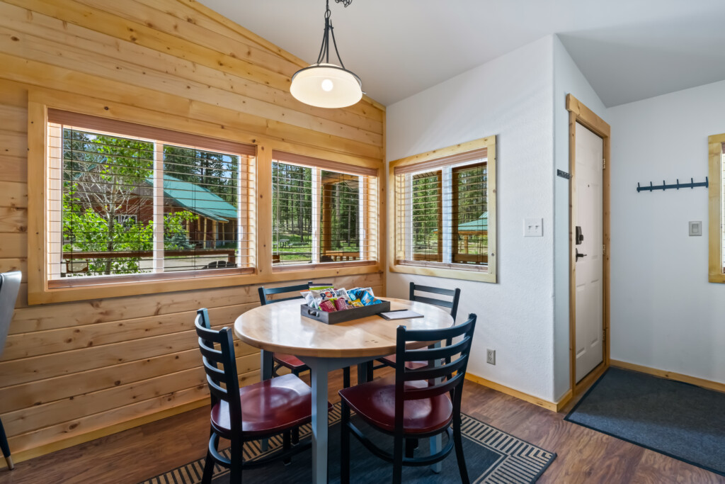 Dining area at Valley Creek Cabin with table and large windows overlooking the trees.
