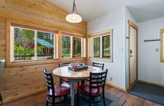 Dining area at Valley Creek Cabin with table and large windows overlooking the trees.